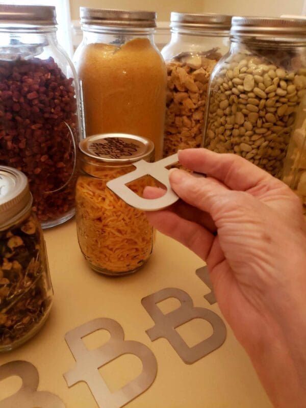 A person holding an object in front of jars.