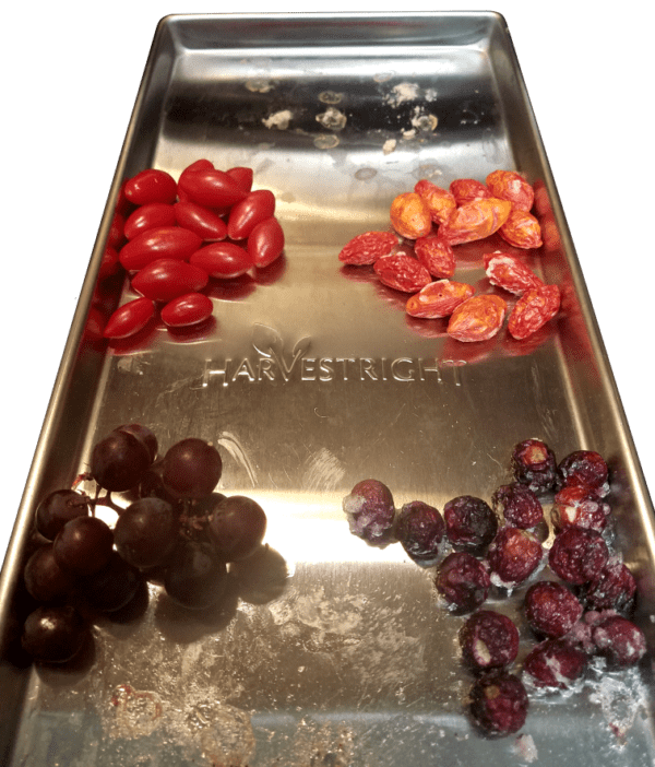 A metal tray with grapes and tomatoes on it.